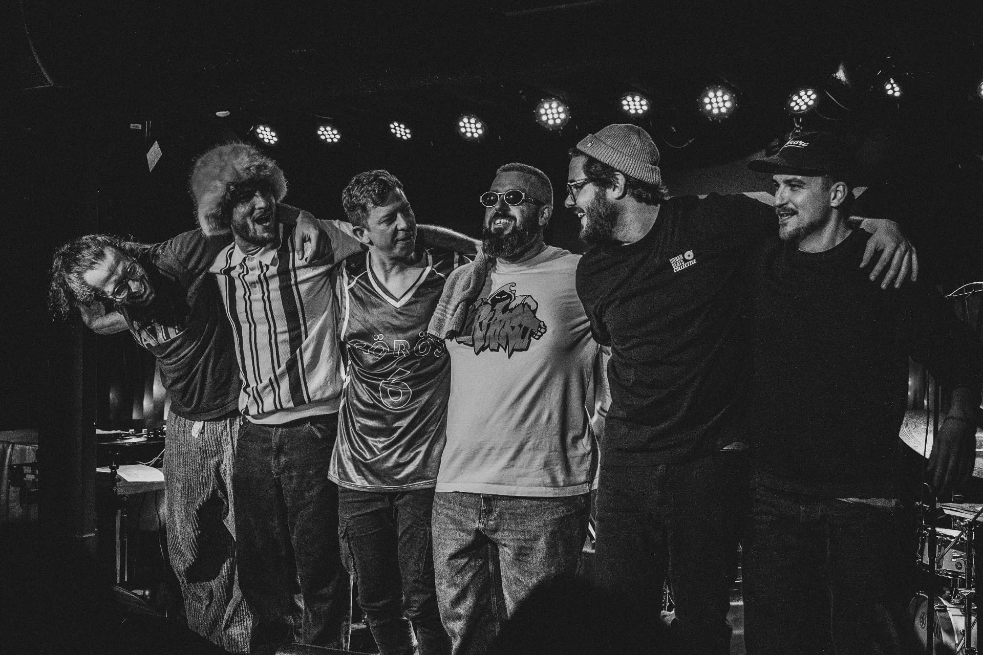 Black-and-white photo of the band arm in arm after a show