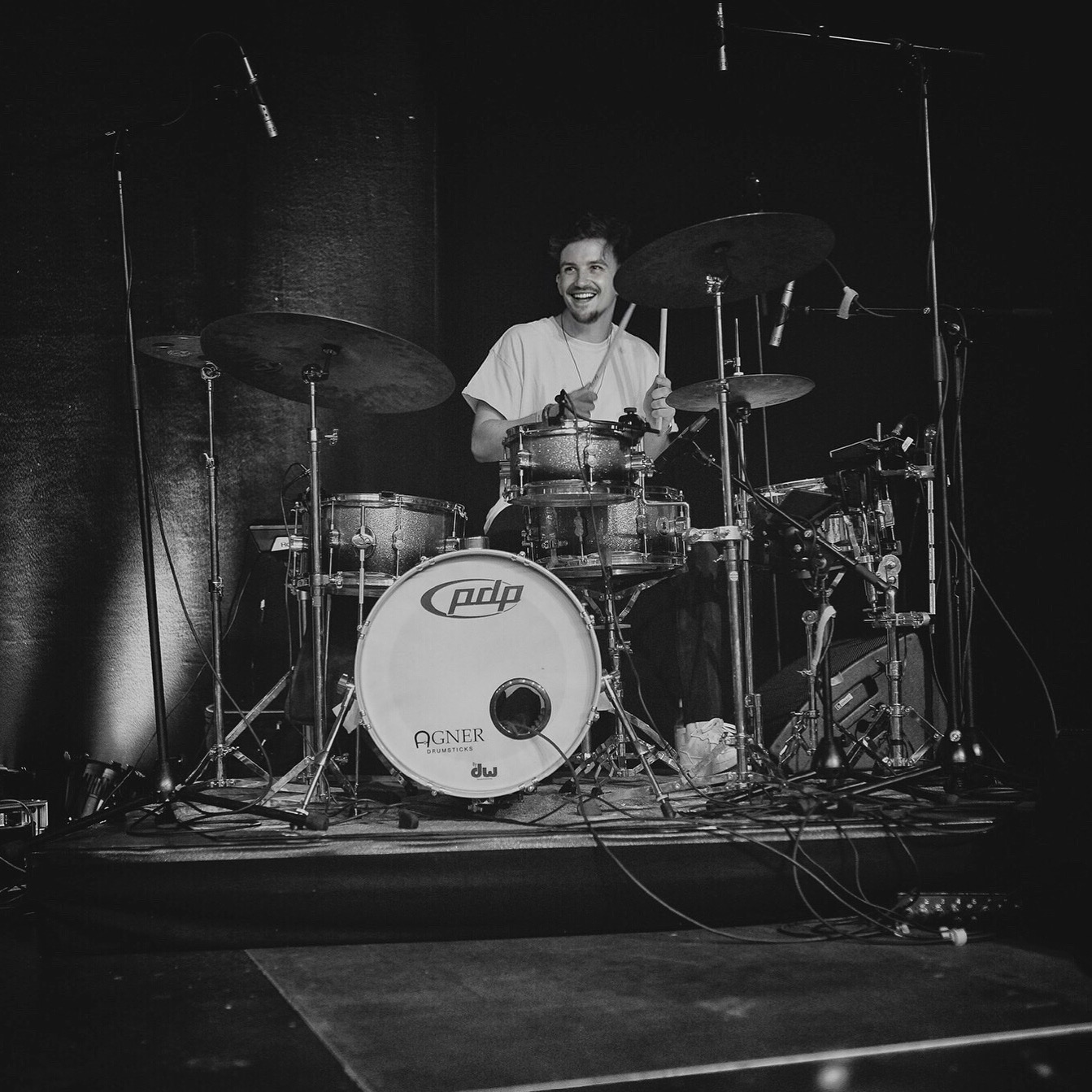 Black-and-white photo of Julian Feuchter laughing behind his drum kit on stage