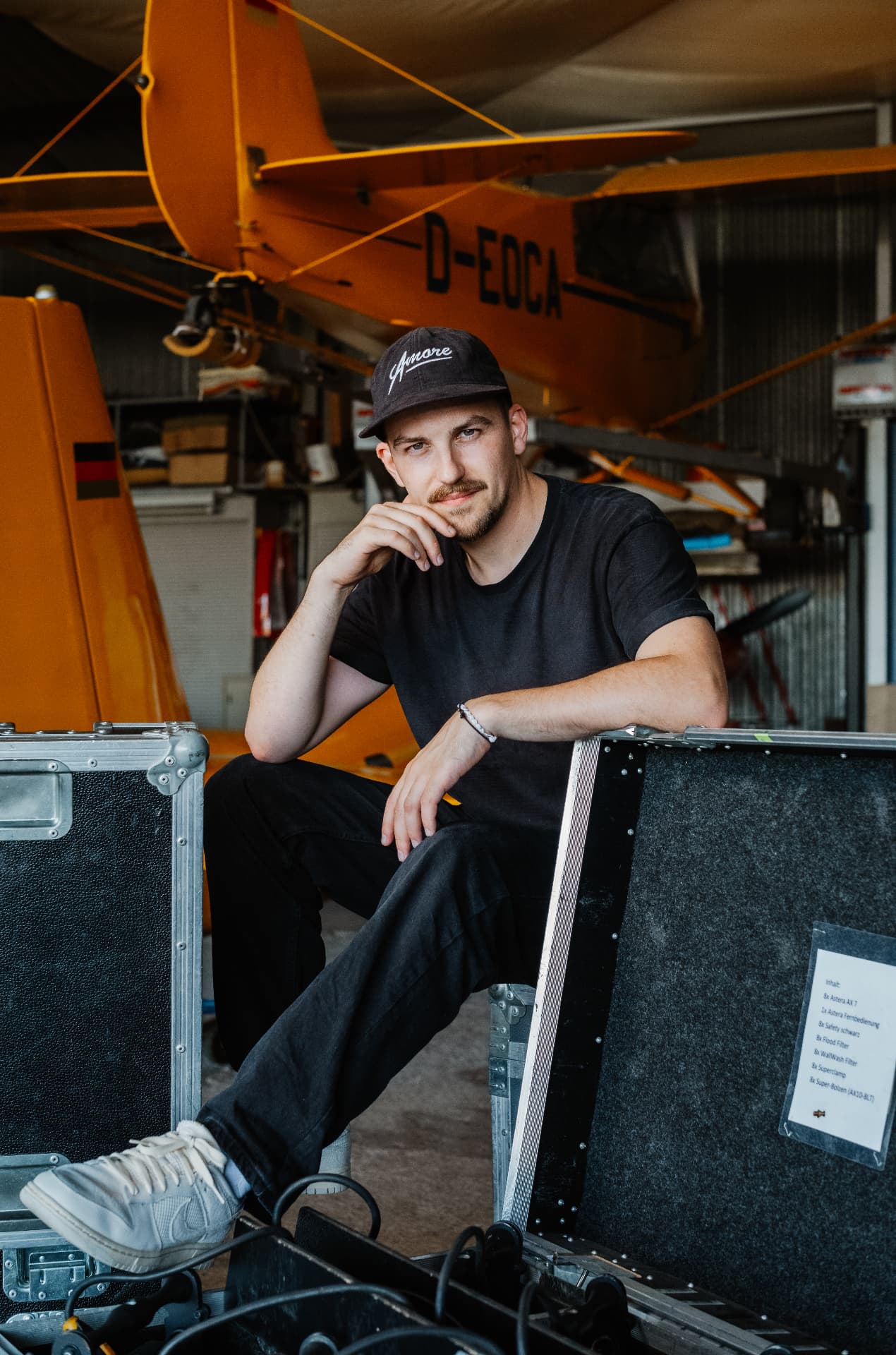 Julian Feuchter seated among touring cases in front of an orange aircraft