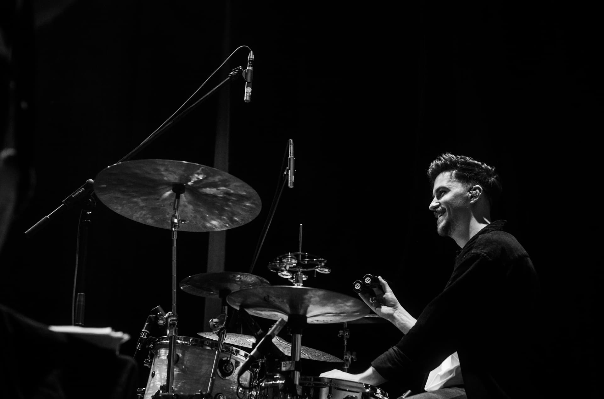 Black-and-white profile of Julian Feuchter smiling at the drums