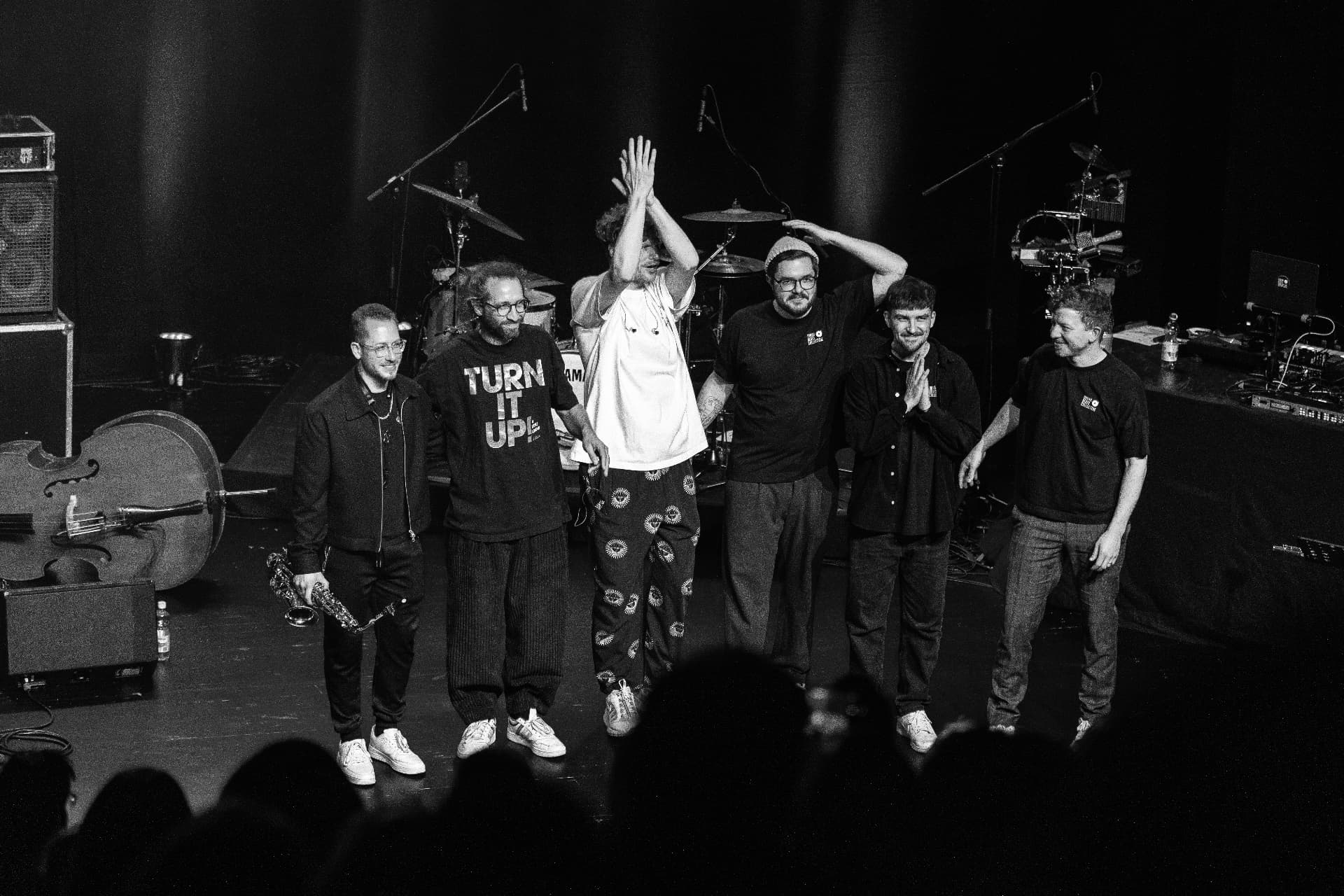 Black-and-white photo of the band taking a bow on stage